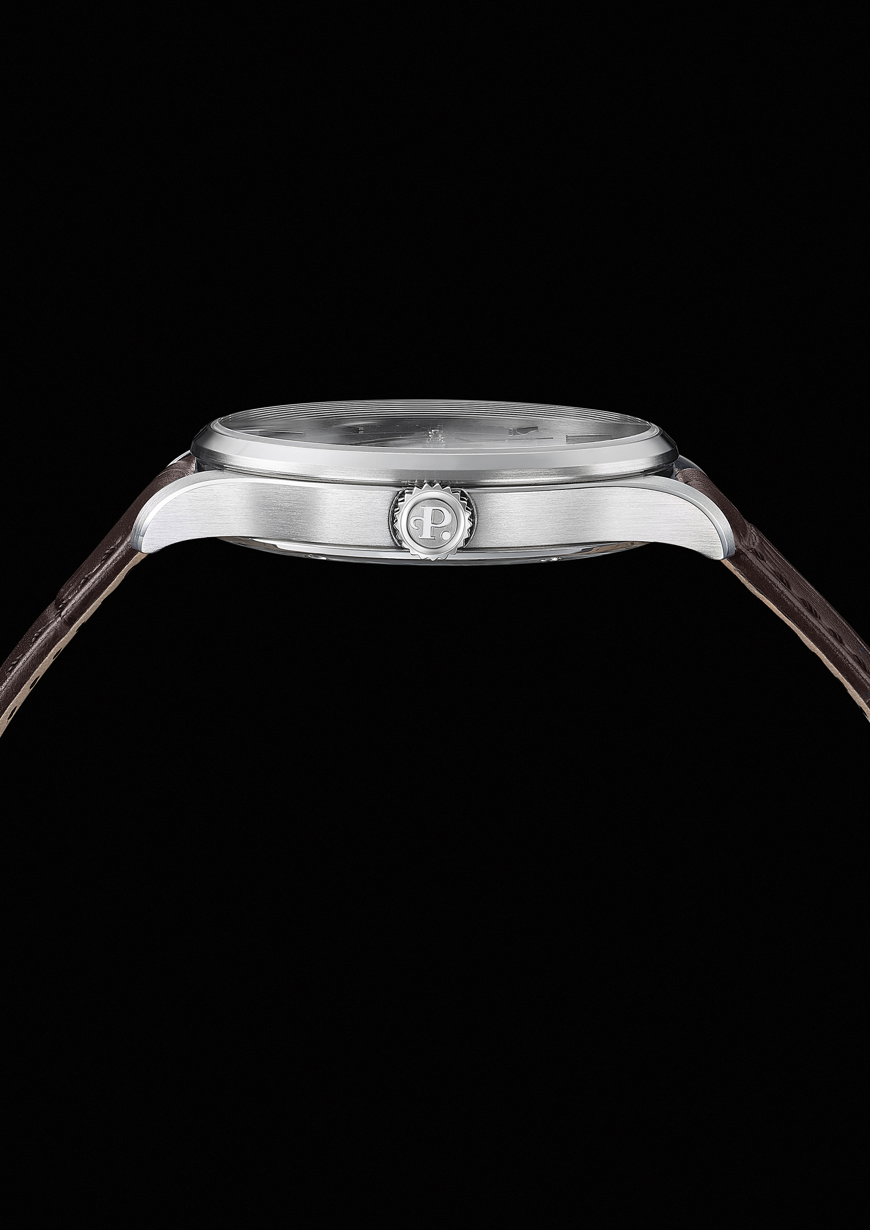 Perfil lateral del reloj mostrando el grosor de la caja de acero inoxidable con acabados cepillados y pulidos. Destaca la corona estriada con el logotipo "P" de Perrelet grabado y la curvatura de las asas sujetando la correa de piel marrón.